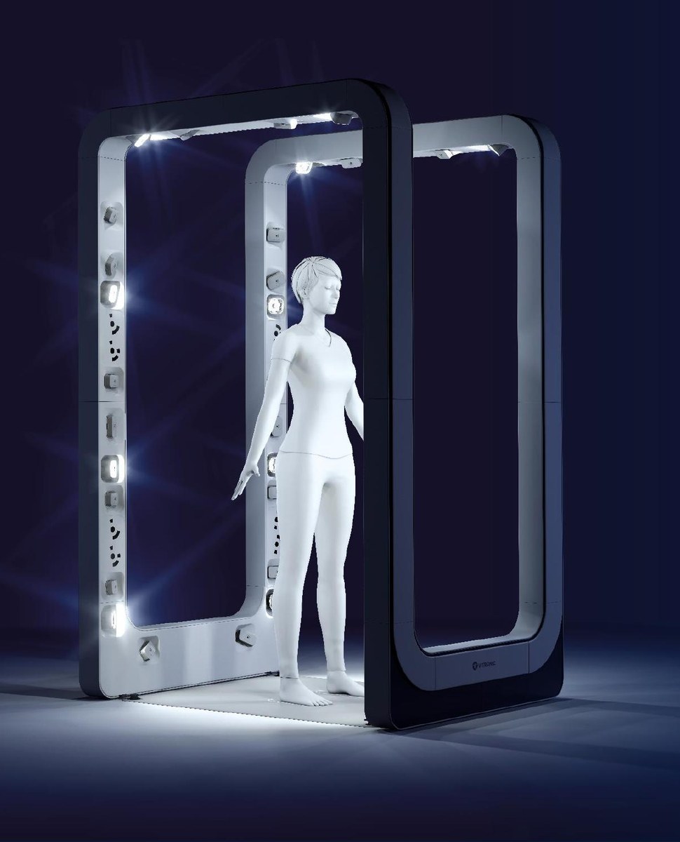 A person standing inside the BodyLoop arch during a scan, sensors and projectors lining the inner face of the arch.